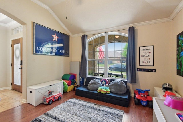 rec room featuring baseboards, arched walkways, ornamental molding, vaulted ceiling, and wood finished floors
