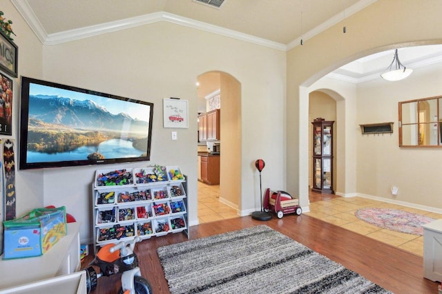 rec room featuring light wood-type flooring, arched walkways, and ornamental molding