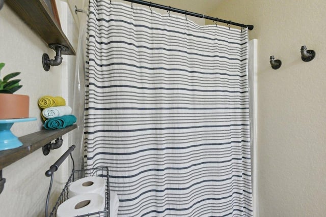 bathroom with a shower with curtain and a textured wall