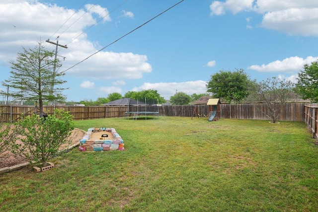 view of yard featuring a fenced backyard, a playground, and a trampoline