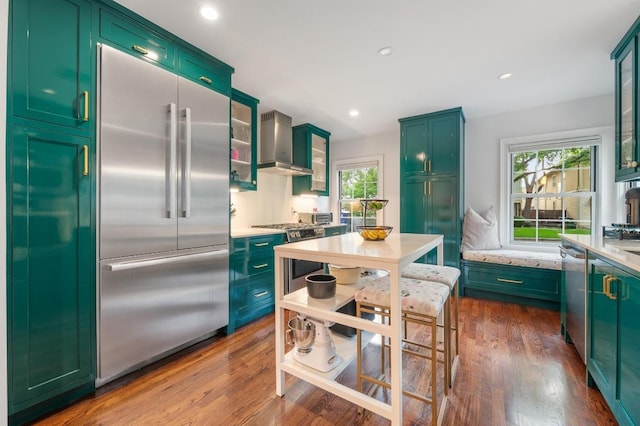 1107 Maufrais St, Austin, TX 78703 - kitchen featuring stainless steel appliances, wall chimney exhaust hood, green cabinetry, plenty of natural light, and recessed lighting