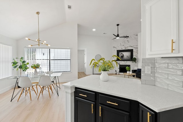 609 Clearwater Trl, Round Rock, TX 78664 - kitchen with a fireplace, dark cabinets, ceiling fan, a peninsula, and lofted ceiling