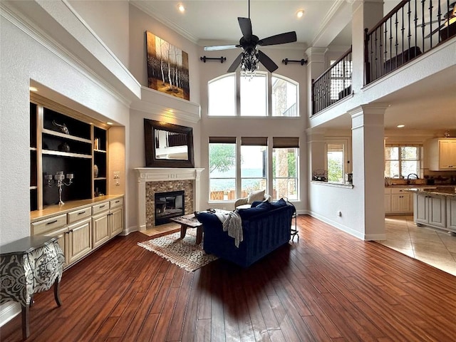 804 Lakewood Hills Ter, Austin, TX 78732 - living room featuring ceiling fan, a fireplace with flush hearth, a high ceiling, crown molding, and light wood-type flooring