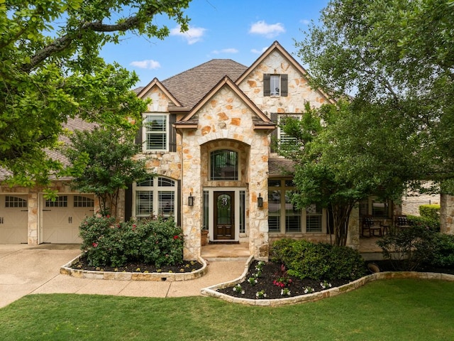 804 Lakewood Hills Ter, Austin, TX 78732 - french country inspired facade with stone siding, a front lawn, concrete driveway, an attached garage, and roof with shingles