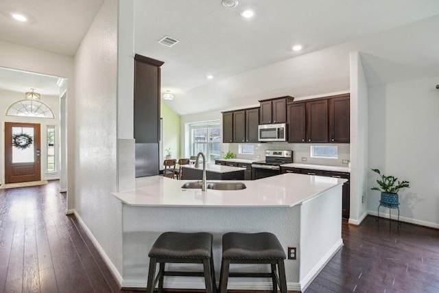 kitchen featuring dark wood-style floors, a sink, stainless steel appliances, dark brown cabinetry, and visible vents