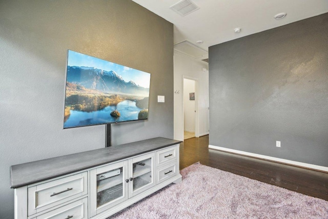 living room with attic access, visible vents, wood finished floors, and baseboards