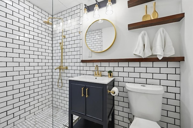 bathroom with vanity, tile walls, toilet, and tiled shower
