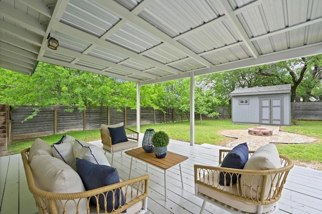 wooden terrace featuring a yard, an outbuilding, a fenced backyard, and an outdoor living space with a fire pit