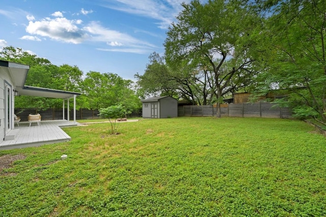 view of yard with a fenced backyard, a storage unit, an outdoor structure, and a deck
