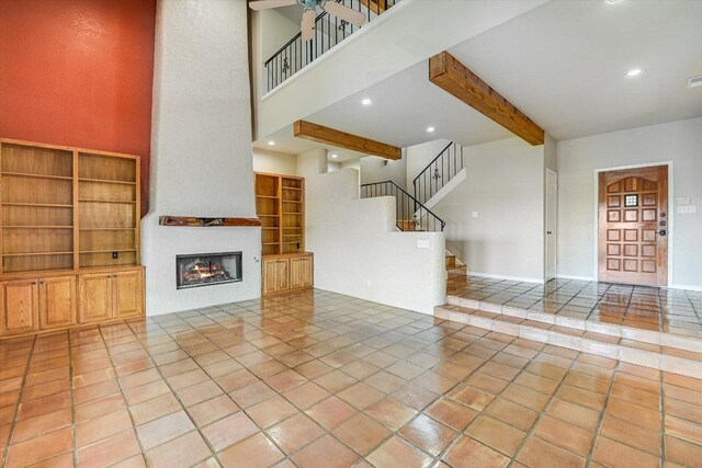 unfurnished living room featuring recessed lighting, a large fireplace, beam ceiling, tile patterned floors, and stairs
