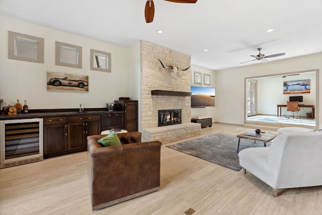 living area featuring beverage cooler, light wood-style floors, and a ceiling fan