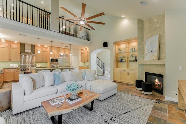 5412 Moon Shadow Dr, Austin, TX 78735 - living room featuring arched walkways, stone tile flooring, visible vents, a ceiling fan, and a towering ceiling