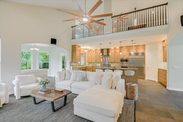 5412 Moon Shadow Dr, Austin, TX 78735 - living area featuring a high ceiling, arched walkways, baseboards, and ceiling fan with notable chandelier