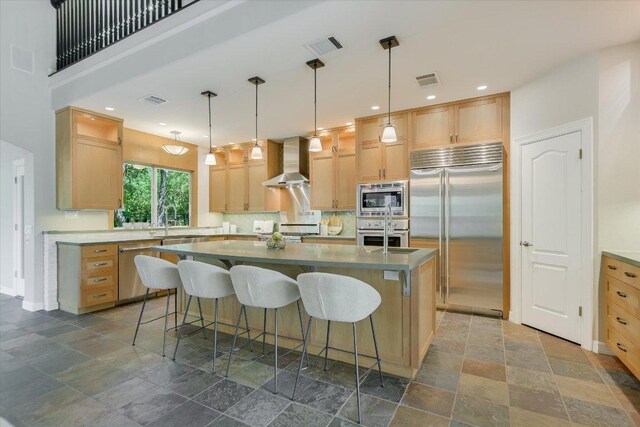 5412 Moon Shadow Dr, Austin, TX 78735 - kitchen with a kitchen island with sink, wall chimney range hood, built in appliances, stone finish flooring, and visible vents
