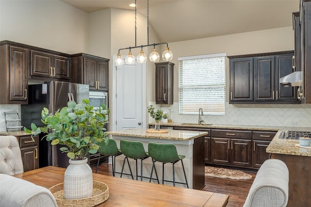 2421 Carretera Dr, Leander, TX 78641 - kitchen with stainless steel appliances, dark brown cabinetry, light stone countertops, decorative backsplash, and lofted ceiling