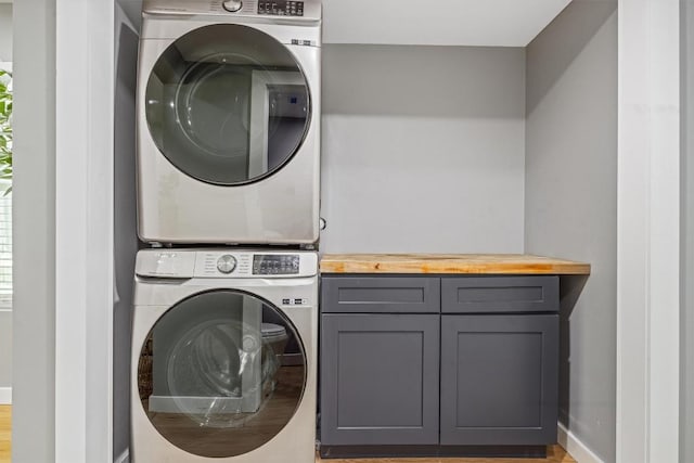 1712 Alleghany Dr, Austin, TX 78741 - washroom featuring stacked washer / drying machine, cabinet space, baseboards, and wood finished floors