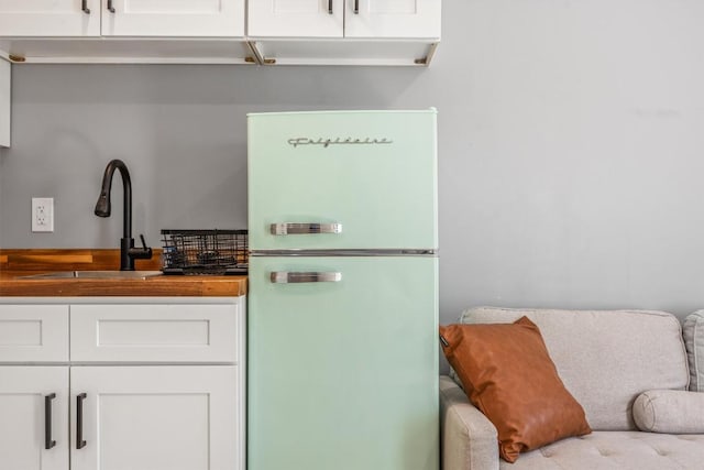 1712 Alleghany Dr, Austin, TX 78741 - kitchen view of freestanding refrigerator, a sink, and white cabinetry