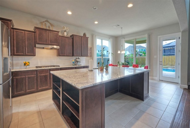 kitchen with open shelves, stainless steel appliances, under cabinet range hood, recessed lighting, and a center island with sink