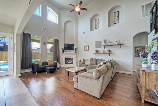 living room featuring visible vents, ceiling fan, and a towering ceiling
