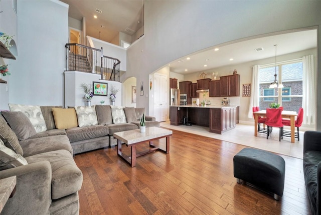 living room featuring visible vents, recessed lighting, light wood finished floors, and arched walkways