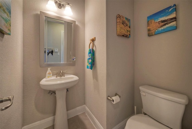 half bath featuring a sink, toilet, and baseboards