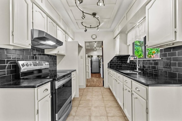 kitchen with white cabinets, dark countertops, appliances with stainless steel finishes, a sink, and under cabinet range hood