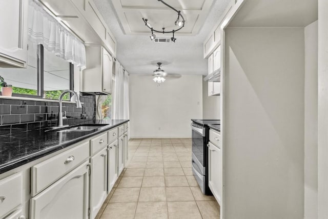 kitchen featuring visible vents, tasteful backsplash, stainless steel range with electric stovetop, a sink, and white cabinetry