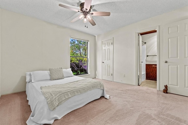 bedroom featuring ensuite bathroom, a textured ceiling, carpet, and ceiling fan