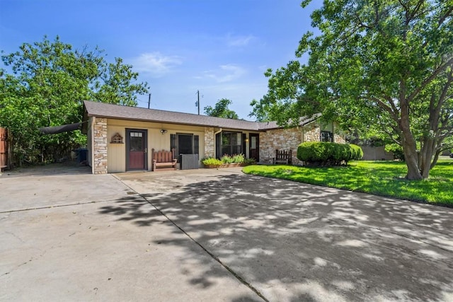 single story home with a front yard, driveway, and stone siding