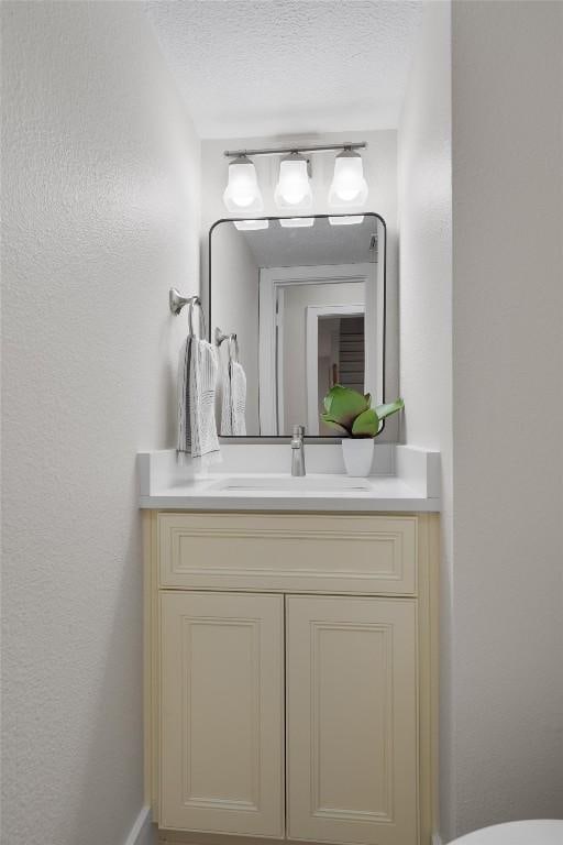 6405 Danwood Dr, Austin, TX 78759 - half bath with vanity, a textured wall, and a textured ceiling