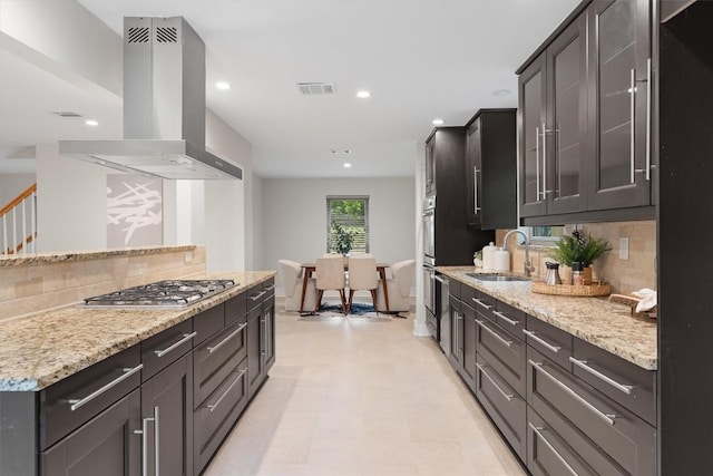 6405 Danwood Dr, Austin, TX 78759 - kitchen with stainless steel appliances, island exhaust hood, backsplash, light stone counters, and glass insert cabinets