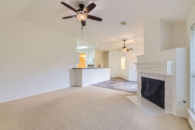 unfurnished living room featuring light tile patterned floors, visible vents, a tile fireplace, light carpet, and a ceiling fan