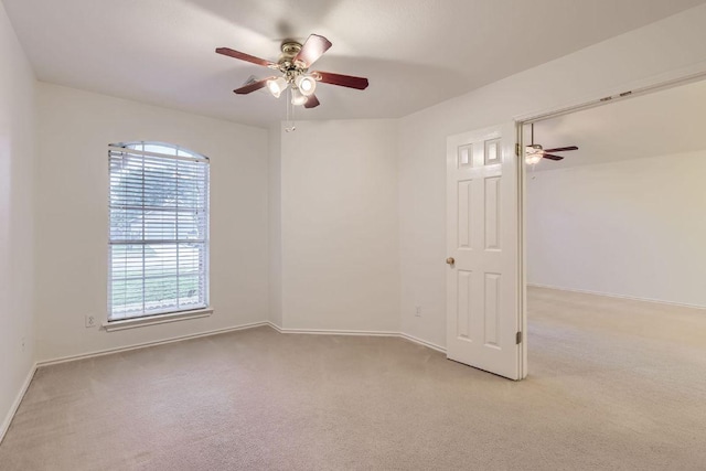empty room featuring baseboards, a ceiling fan, and light colored carpet