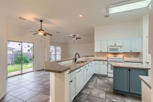 kitchen featuring white appliances, ceiling fan, a sink, visible vents, and a peninsula