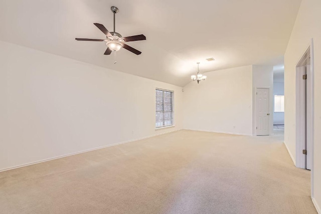 empty room featuring lofted ceiling, light colored carpet, baseboards, and ceiling fan with notable chandelier