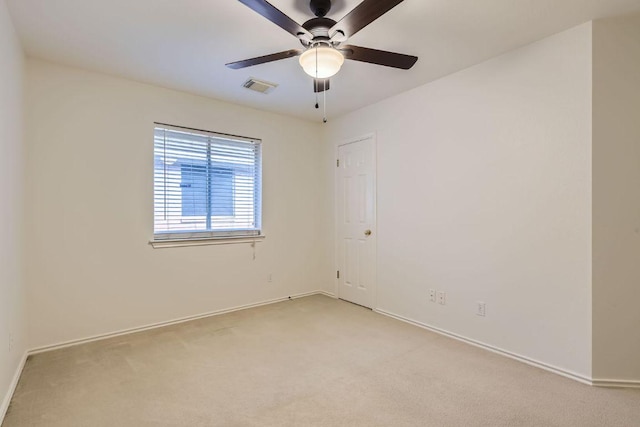 empty room with baseboards, visible vents, a ceiling fan, and light colored carpet