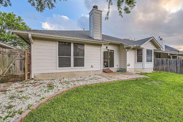back of property featuring entry steps, a chimney, a patio area, a lawn, and fence