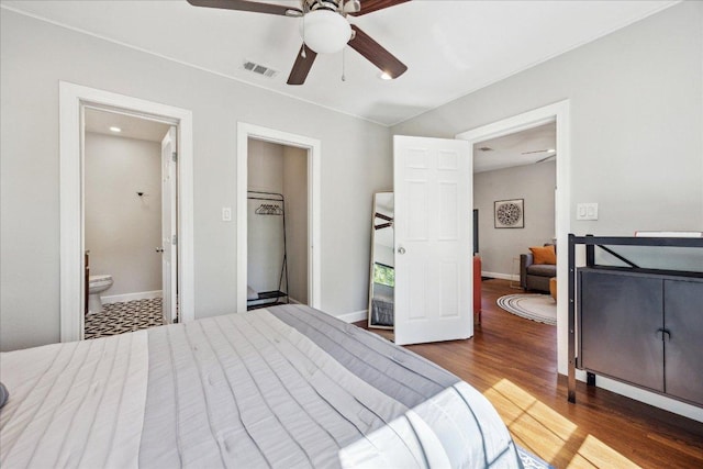 bedroom with wood finished floors, ceiling fan, ensuite bathroom, baseboards, and visible vents