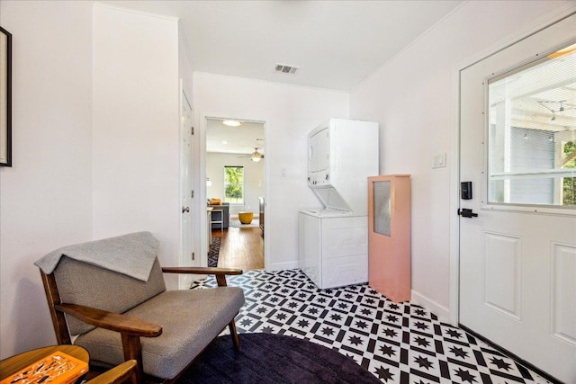 foyer featuring stacked washer / drying machine, ceiling fan, visible vents, baseboards, and tile patterned floors