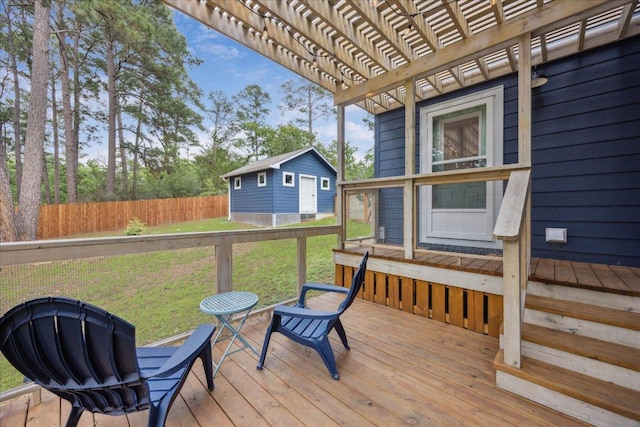 deck featuring a pergola, fence, an outbuilding, and a lawn