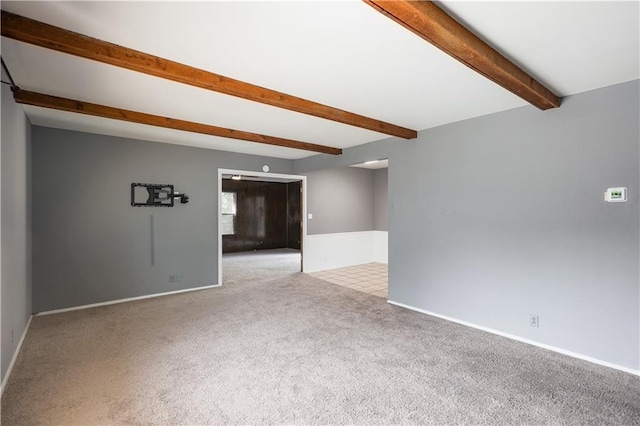 unfurnished room featuring beam ceiling, carpet, and baseboards