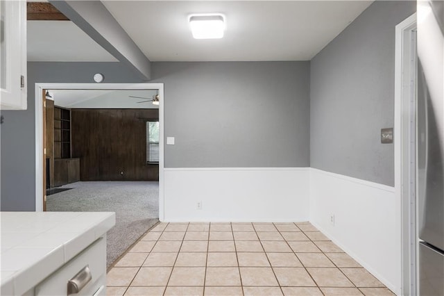 interior space with light tile patterned floors, light carpet, and ceiling fan