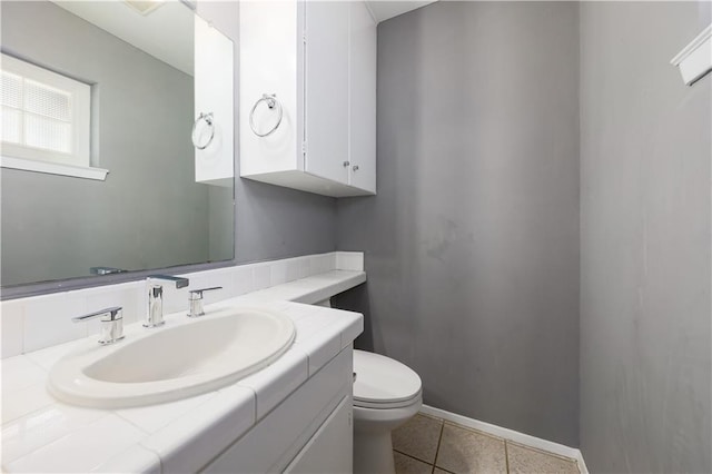 half bathroom with vanity, toilet, tile patterned flooring, and baseboards