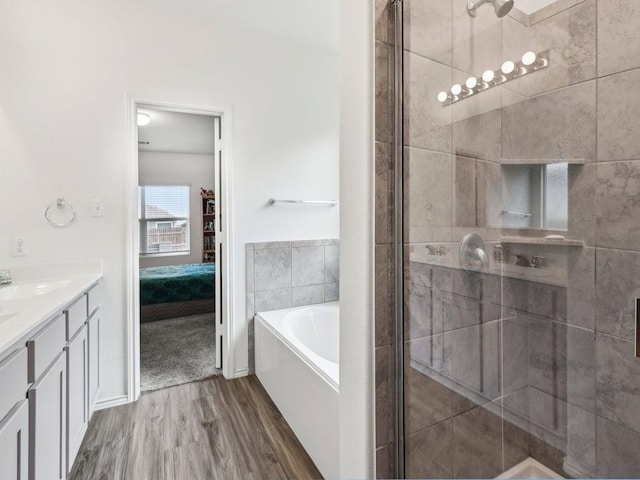 ensuite bathroom with vanity, a stall shower, a garden tub, wood finished floors, and ensuite bathroom
