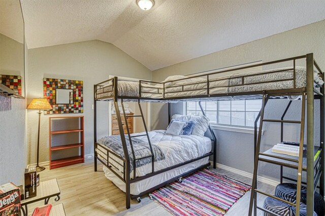 609 E Briarway Dr, Granite Shoals, TX 78654 - bedroom featuring vaulted ceiling, wood finished floors, a textured ceiling, a textured wall, and baseboards