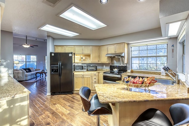 609 E Briarway Dr, Granite Shoals, TX 78654 - kitchen featuring stainless steel appliances, light brown cabinets, under cabinet range hood, wood finished floors, and a peninsula
