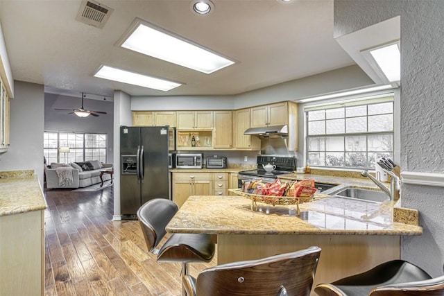 609 E Briarway Dr, Granite Shoals, TX 78654 - kitchen featuring a sink, under cabinet range hood, light brown cabinets, a textured wall, and appliances with stainless steel finishes