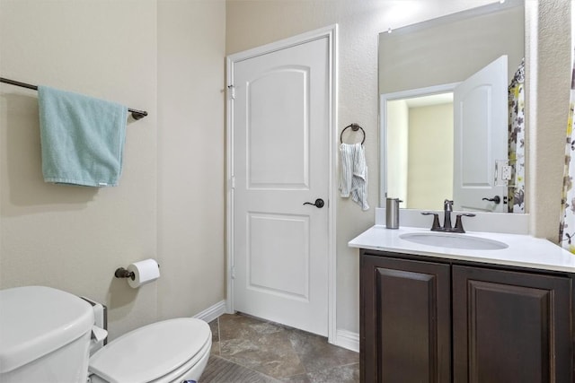 bathroom with toilet, vanity, and baseboards