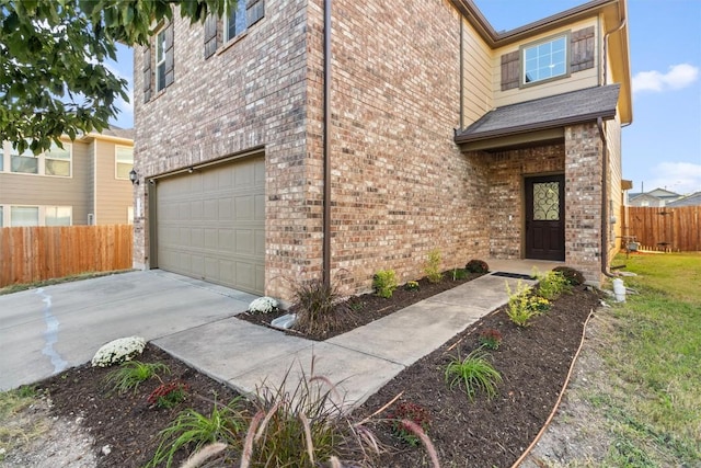 exterior space with concrete driveway, fence, an attached garage, and brick siding
