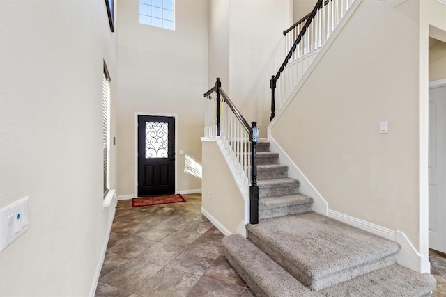 entryway featuring baseboards, a high ceiling, and plenty of natural light